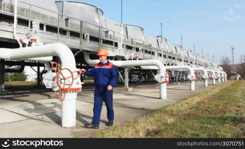 worker closes valve on installation for cooling gas at compressor station of main pipeline