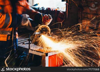 Worker cutting metal with grinder in his workshop. Sparks while grinding iron.. Worker cutting metal with grinder in his workshop. Sparks while grinding iron