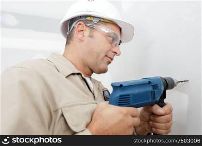 worker drilling a hole into the wall
