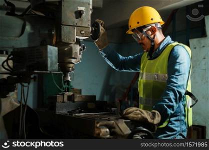 worker Drilling machine hole metal flat steel plate and selective focus with bench drill in the factory