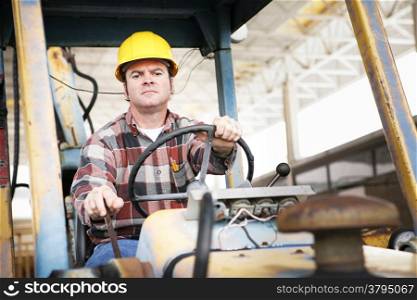 Worker driving heavy construction equipment - bulldozer or backhoe.