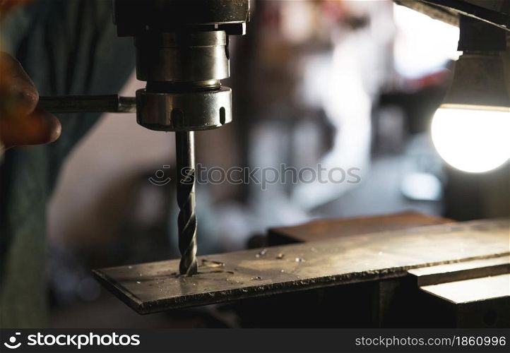Worker hand working on milling machine to change metal drill bit. Tool for drilling metal workpiece. Milling machine. Steel manufacturing industry. Metal work industry. Industrial drilling machine.