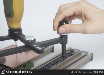 Worker hands on Engraving device pantograph with CNC engraver with letterpress alphabet on a white background. Worker hands on Engraving device pantograph with CNC engraver with letterpress alphabet