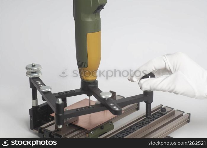 Worker hands on Engraving device pantograph with CNC engraver with letterpress alphabet on a white background. Worker hands on Engraving device pantograph with CNC engraver with letterpress alphabet