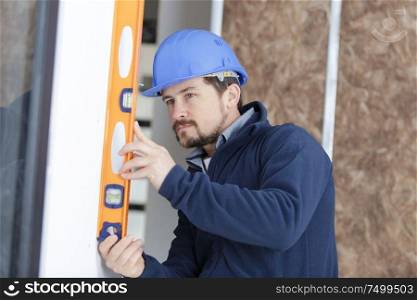 worker in blue uniform measures the wall