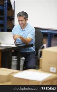 Worker In Distribution Warehouse Using Laptop