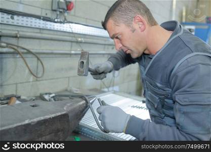 worker in factory with hammer on work bench