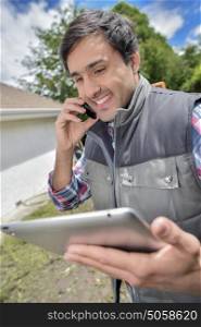 Worker in garden on telephone, holding tablet