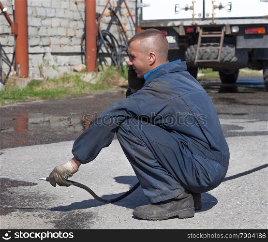Worker in overalls watering the paved area with water