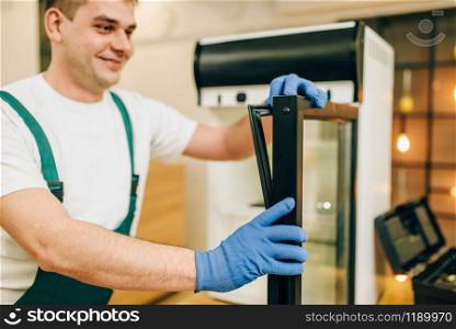 Worker in uniform repair refrigerator at home. Repairing of fridge occupation, professional service