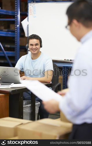 Worker In Warehouse Wearing Headset And Using Laptop