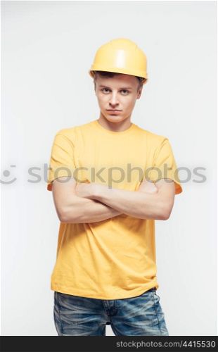 Worker in yellow helmet standing with arms crossed