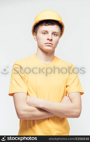 Worker in yellow helmet standing with arms crossed