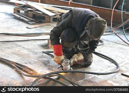 Worker is cutting metal by grinder