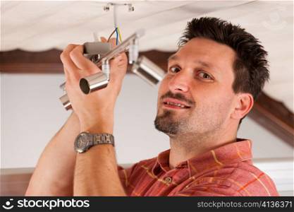 Worker is installing a luster on the ceiling