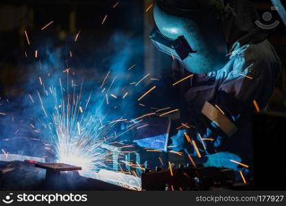 Worker is welding assembly part in car factory