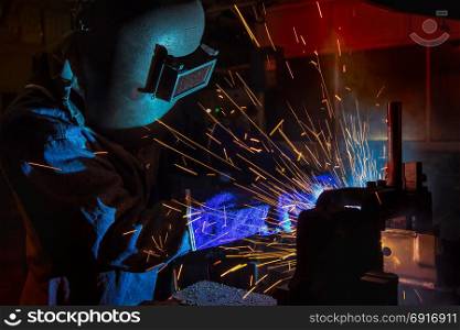 Worker is welding in car factory