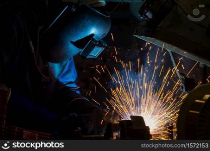 Worker is welding steel part in factory