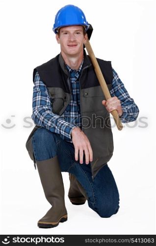 Worker kneeling with sledge-hammer over shoulder