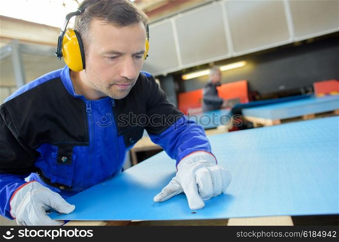 Worker looking at mark on sheet of materials
