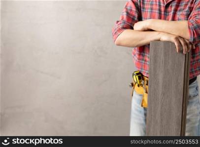 Worker man holding laminate in house room renovation. Male hand and wood laminate near concrete or plaster wall. Home renovation concept