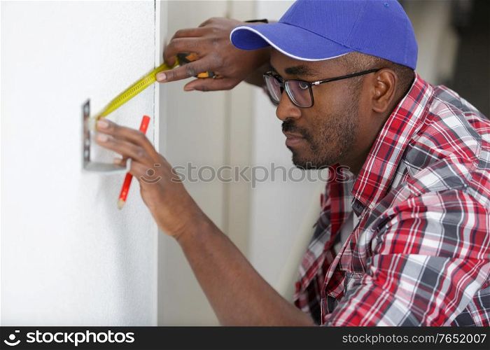worker man using tape measure on door frame