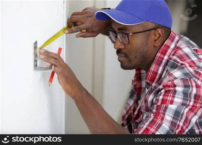 worker man using tape measure on door frame