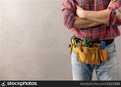 Worker man with tool belt near concrete or cement wall. Male hand and tools for house room renovation. Home renovation concept