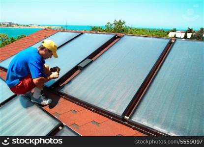 Worker mounting solar water heating panels on the roof.