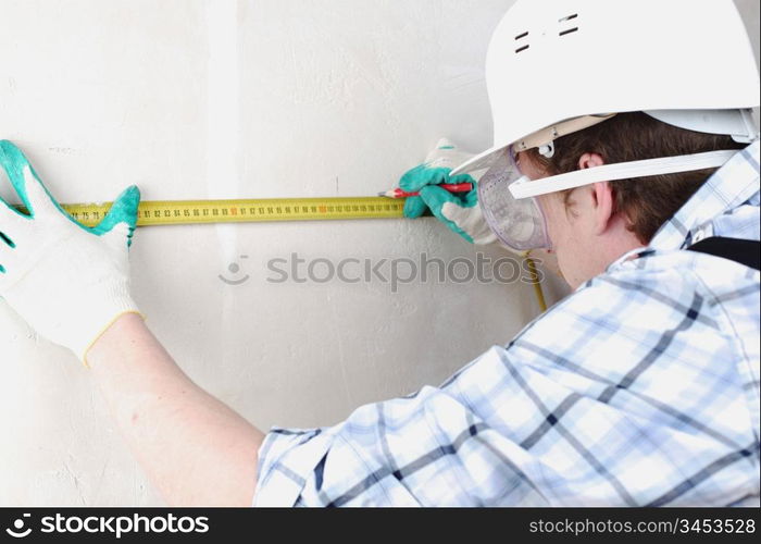 worker often with a measuring tape to the wall