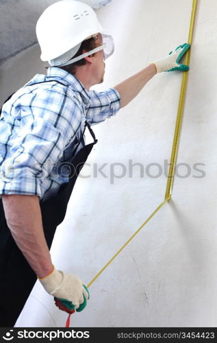 worker often with a measuring tape to the wall