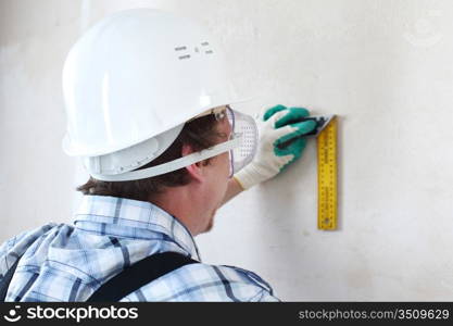 worker often with a measuring tape to the wall