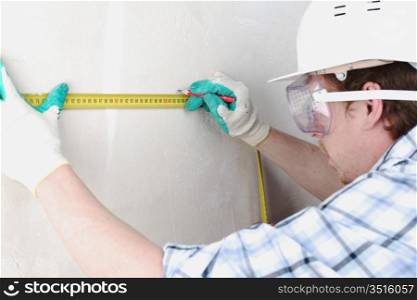 worker often with a measuring tape to the wall