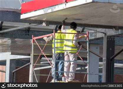 worker on a scaffold scraping off under roofing