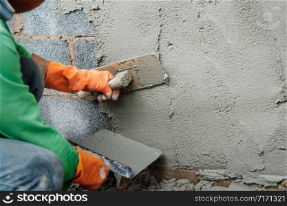 worker plastering cement on wall for building house