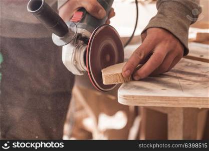 Worker polishing wood table where carpenter hands sanding a wood with electric sander. Sander for wood