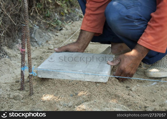 Worker puts sidewalk tiles. Walkway making