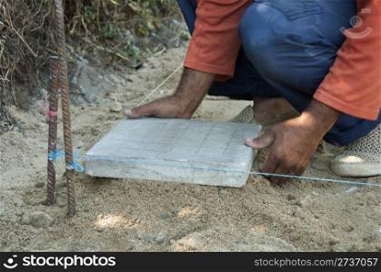 Worker puts sidewalk tiles. Walkway making