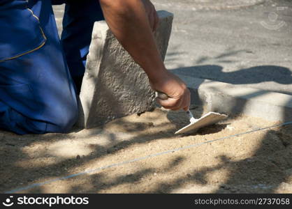 Worker puts sidewalk tiles. Walkway making