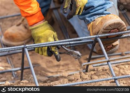 Worker Securing Steel Rebar Framing With Wire Plier Cutter Tool At Construction Site.