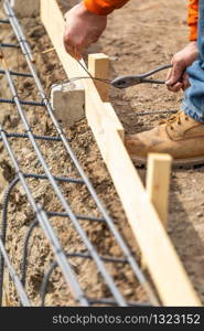 Worker Securing Steel Rebar Framing With Wire Plier Cutter Tool At Construction Site.