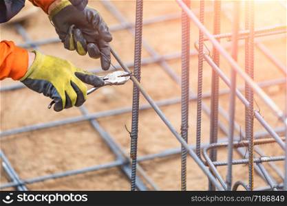 Worker Securing Steel Rebar Framing With Wire Plier Cutter Tool At Construction Site.