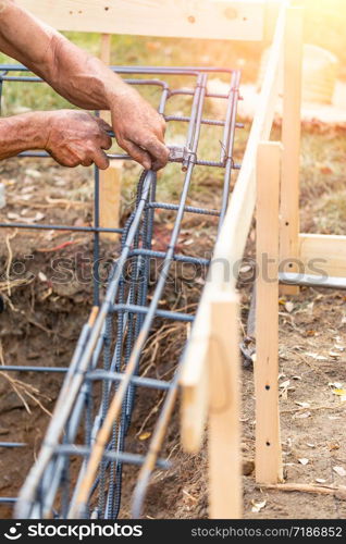 Worker Securing Steel Rebar Framing With Wire Plier Cutter Tool At Construction Site.