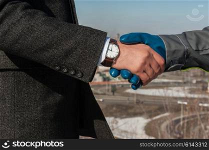 worker shakes hands with businessman. Industry worker with glove shakes hands with businessman