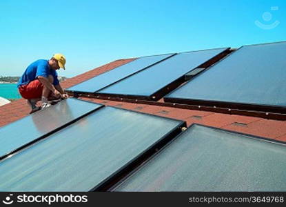 Worker solar water heating panels on the roof.