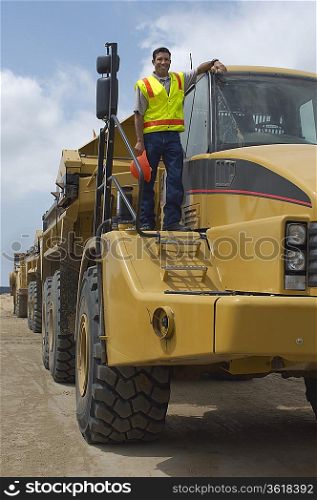 Worker standing on truck at landfill site, portrait