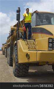 Worker standing on truck at landfill site, portrait