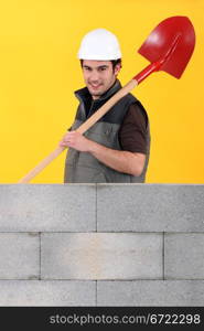 Worker stood by wall with spade