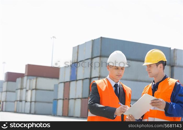 Worker taking sign of supervisor on clipboard in shipping yard