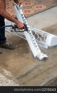 Worker to cleaning coil cooler of air conditioner by water for clean a dust on the wall in customer home when maintenance service. Cleaning air conditioner by water for clean a dust